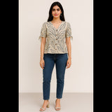 Woman wearing a beige printed peplum top with puff sleeves and tie-up details, paired with jeans.
