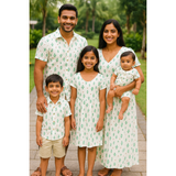 Indian family in coordinated white cactus print cotton outfits – mom, dad, son, daughter, and baby smiling outdoors in matching family wear