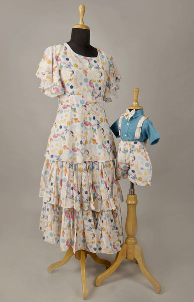 Mom and Baby Boy in Matching Tropical Bird Print Outfits – White Printed Dress with Ruffles and Coordinated Baby Boy Suspender Set