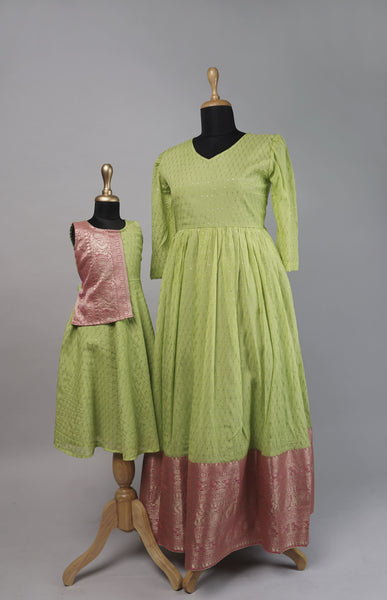 Mom and daughter wearing matching green and pink ethnic combo dresses with shimmer fabric and brocade detailing - perfect for festive occasions.