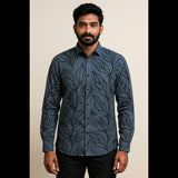 Man wearing blue shirt with black leaf print and black trousers, full-sleeve button-down style