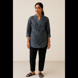 Indian woman wearing a charcoal grey cotton tunic top with black embroidered leaf design, paired with black trousers.