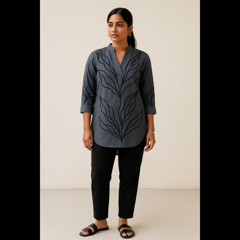 Indian woman wearing a charcoal grey cotton tunic top with black embroidered leaf design, paired with black trousers.