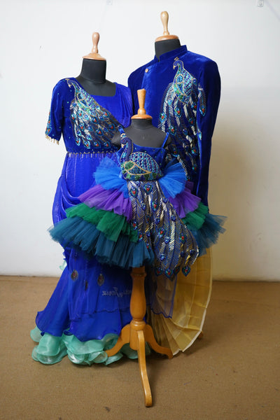 Royal blue coordinated family outfit with peacock embroidery – includes dad's sherwani, mom's saree gown, and baby's tutu dress.