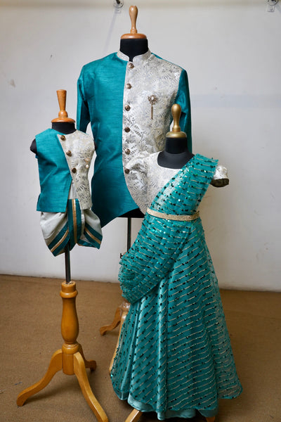 Family ethnic outfit set in teal and ivory featuring kurta, saree, lehenga, and dhoti for dad, mom, son, and daughter.