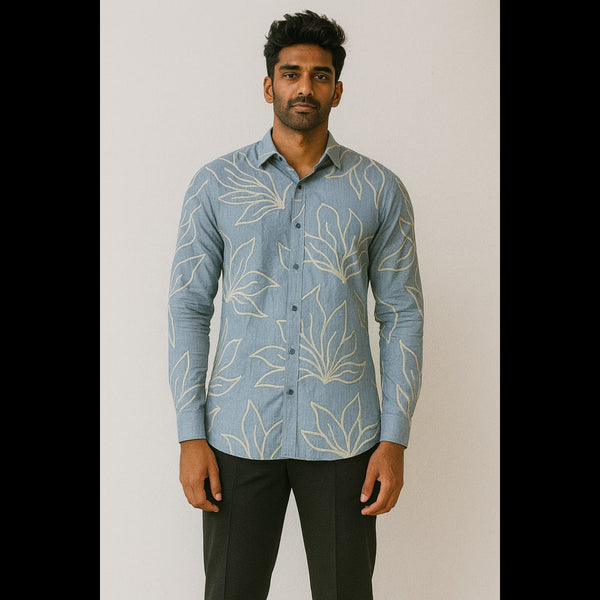 Man wearing a sky blue embroidered leaf-pattern shirt paired with black trousers