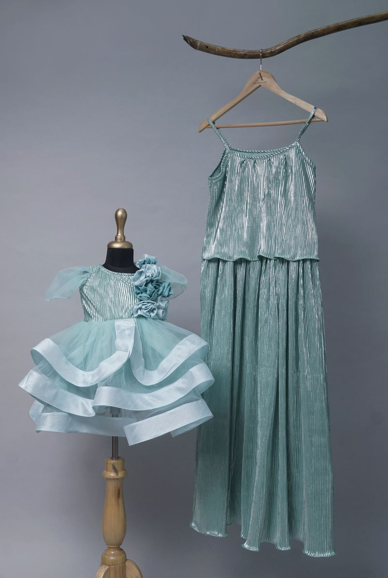Mom and daughter wearing matching Aqua Green Metallic Party Wear outfits — mom in strappy metallic pleated maxi dress, daughter in layered frock with flowers.