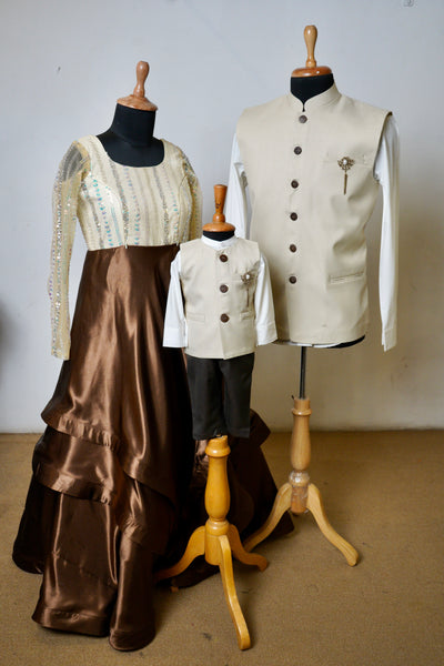 Family outfit set featuring an ivory and mocha brown gown for mom, ivory Nehru jacket for dad, and matching 3-piece outfit for boy.