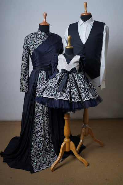 Family outfit set with black and silver embroidery – saree gown for mom, waistcoat look for dad, and flared frock for daughter
