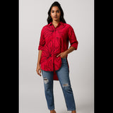 Woman wearing bold red floral oversized shirt with ripped jeans – front view
