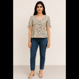 Woman wearing a beige printed peplum top with puff sleeves and tie-up details, paired with jeans.