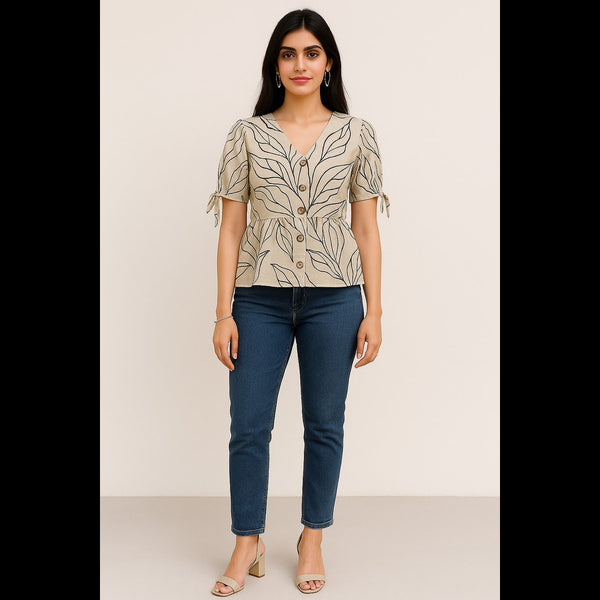 Woman wearing a beige printed peplum top with puff sleeves and tie-up details, paired with jeans.