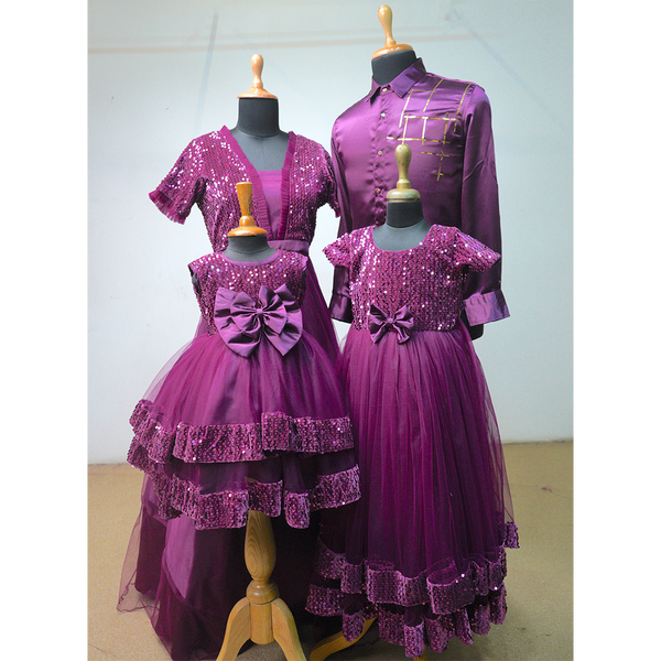 Purple sequin family outfit set including men’s kurta shirt, women’s long gown, and two girls’ dresses with bows and shimmer.