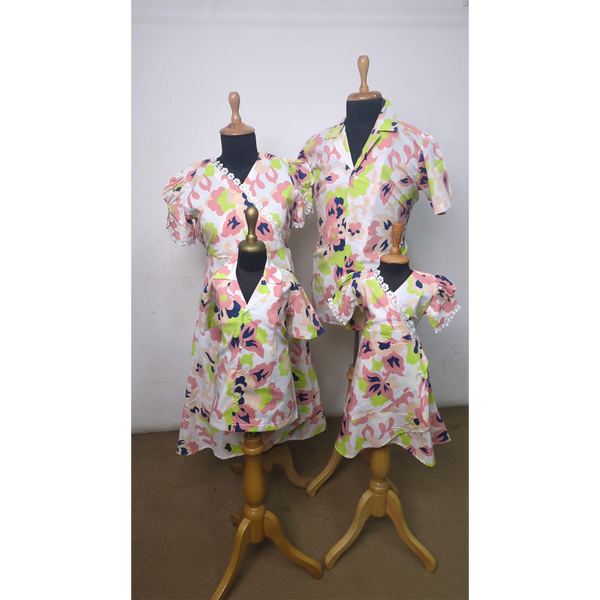 Family outfit set in abstract pink and lime floral print featuring coordinated dresses for mother and daughters, and a shirt for father – styled on mannequins.