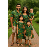 Indian family in coordinated green floral cotton outfits – dad, mom, baby, son, and daughter in cheerful matching dresses and shirts standing on a garden path