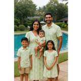 Indian family in matching light green bamboo print cotton outfits – mom, dad, son, daughter, and baby posing together by a pool