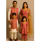Family wearing coordinated pink and cream raw silk ethnic outfits — father, mother, son, and daughter dressed in matching traditional festive attire.